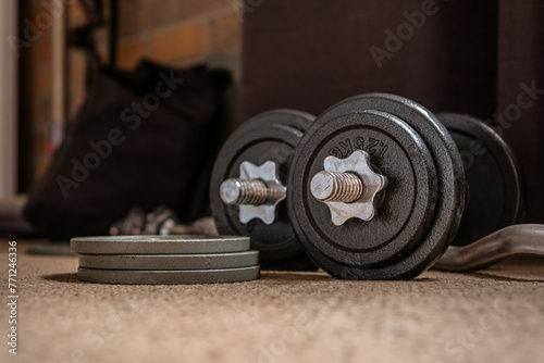 Fototapeta Naklejka Na Ścianę i Meble -  Old used gym weights. Close up of worn dumbbell, fitness equipment in run down gymnasium