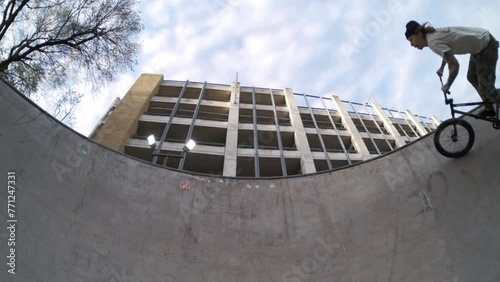 BMX rider wall riding skatepark bowl sideways in extreme 800fps slow motion, static wide symmetrical fisheye in 4k photo