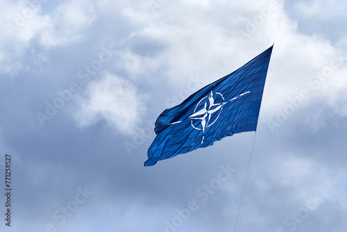 NATO flag on cloudy sky. Flying in the sky