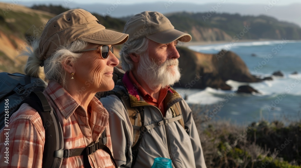 Elderly senior smiling active couple with backpacks enjoying hiking and walking along coastline near mountains and sea or ocean, active retirement lifestyle filled with outdoor adventures. Elderly senior smiling active couple with backpacks enjoying hiking and walking along coastline near mountains and sea or ocean, active retirement lifestyle filled with outdoor adventures.