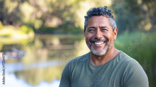 Latino american man in his 50s who exudes happiness and a sense of feeling truly alive in a beautiful natural park near lake, genuine smile on his face, relaxed and confident latin male who found joy