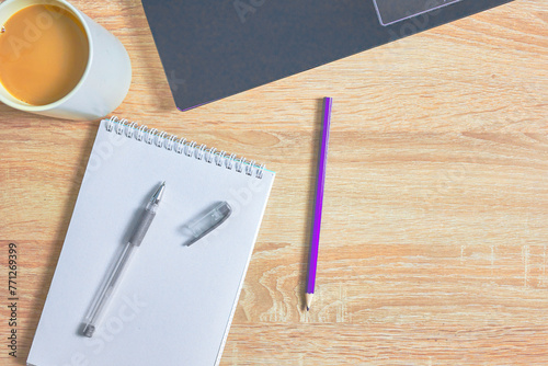 an open notepad for notes, a fountain pen, a pencil , a cup of coffee and a laptop on a wooden table with a copy space, top view