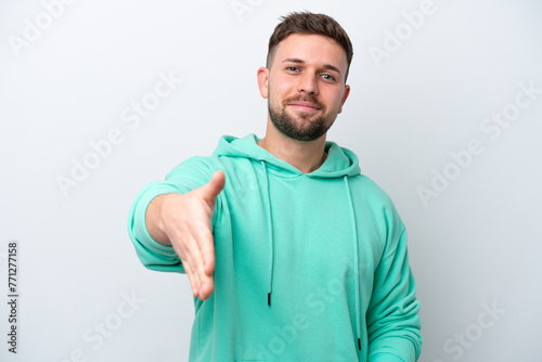 Young caucasian man isolated on white background shaking hands for closing a good deal