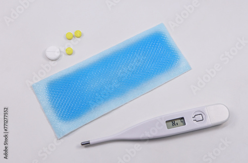 Medical digital thermometer, Cooling fever patch gel and medicinal pills on white background. basic medical tools concept