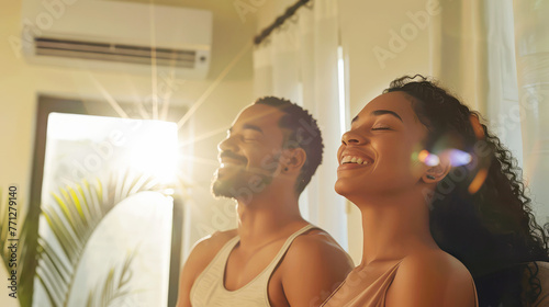 happy young man and woman enjoying the rays of the sun at home on a hot summer day. climate in the house photo