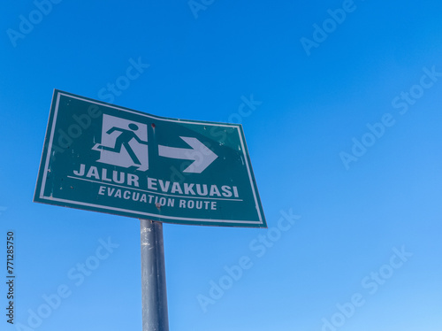 warning board with jalur evakuasi writing in English evacuation route on a clear blue sky background photo