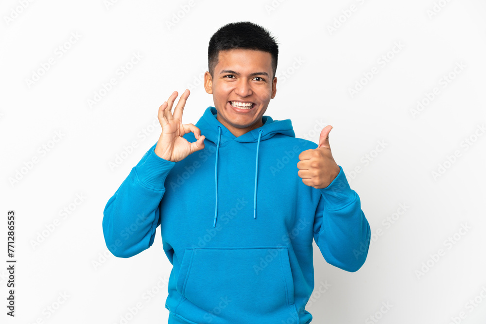 Young Ecuadorian man isolated on white background showing ok sign and thumb up gesture Young Ecuadorian man isolated on white background showing ok sign and thumb up gesture