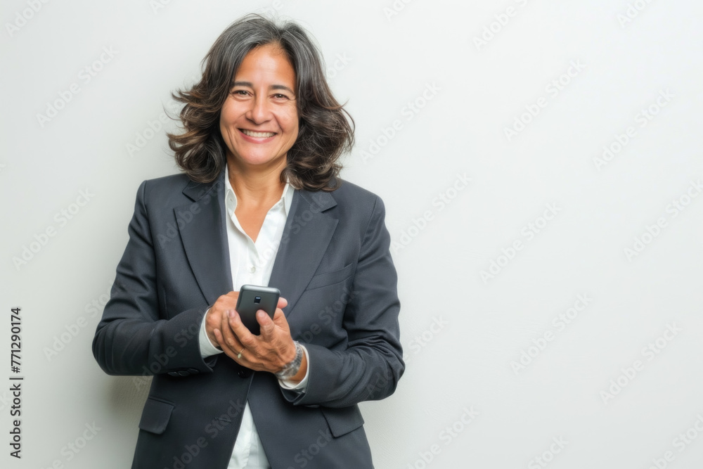 Mature Hispanic Businesswoman Using Smartphone, Smiling with Confidence Mature Hispanic Businesswoman Using Smartphone, Smiling with Confidence