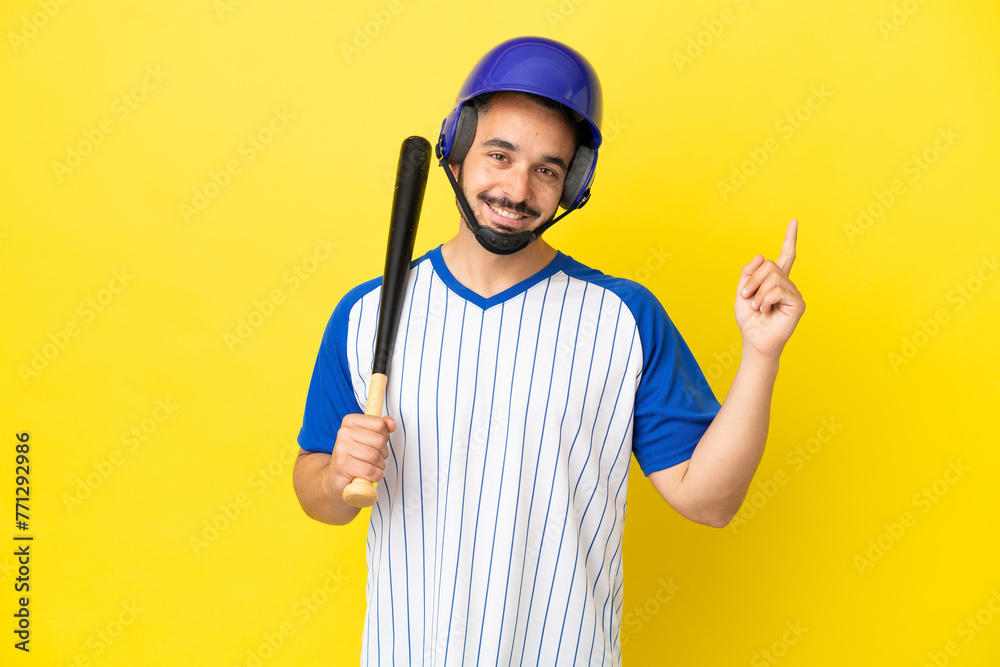 Young caucasian man playing baseball isolated on yellow background showing and lifting a finger in sign of the best