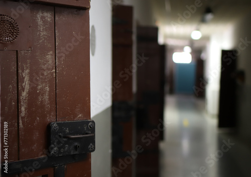 a gloomy prison corridor with the doors of the detention cells ajar