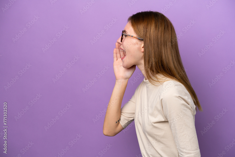 Young English woman isolated on purple background shouting with mouth wide open to the side Young English woman isolated on purple background shouting with mouth wide open to the side
