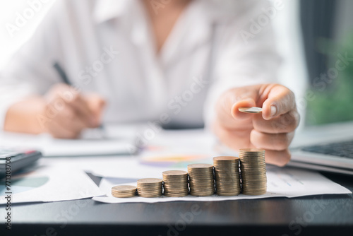 Human hand stacking coins over office background. Concept of investment management and portfolio diversification. Business diagram on financial report with coins.