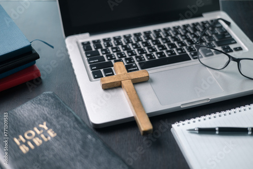 Cross on bible and laptop in online study bible concept. Holy Bible concept for modern religious education, podcast or help with hearing for blind studying photo