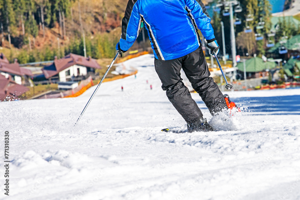 skier starts down a snowy slope on a sunny day. Active family vacation