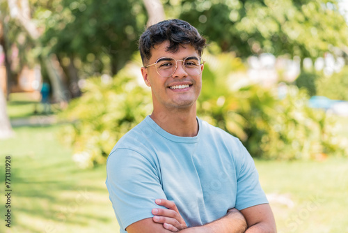 Young hispanic man at outdoors With glasses with happy expression