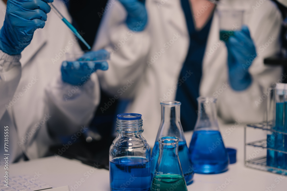 Fototapeta premium Team of biochemical research scientists working with a microscope for vaccine development in pharmaceutical research labeling.