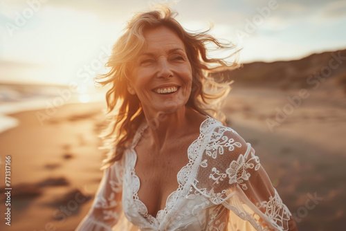 A woman is smiling and wearing a white lace dress on a beach