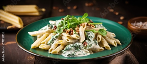 Delicious whole wheat penne pasta topped with creamy gorgonzola cheese sauce, fresh spinach, and crunchy walnuts served on a vibrant green plate photo
