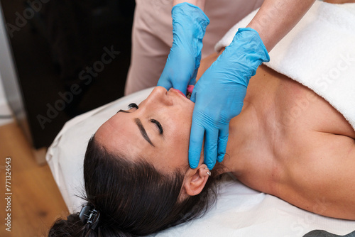 Clinic session of TMJ therapy with expert manual treatment on jaw.