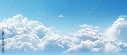 A commercial airplane is soaring high amidst the serene blue sky filled with fluffy white clouds, creating a picturesque scene
