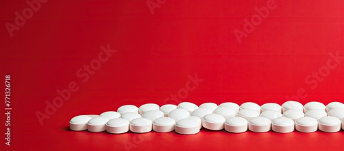 White circular medical tablets neatly organized in a straight line on a vibrant red surface, emphasizing order and medication