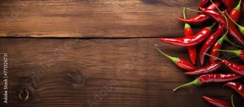 A close-up view of a variety of red hot peppers arranged on a rustic wooden table in natural light photo