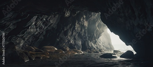 Bright light illuminating the interior of a large cave, showing a unique rock formation amidst the dimness