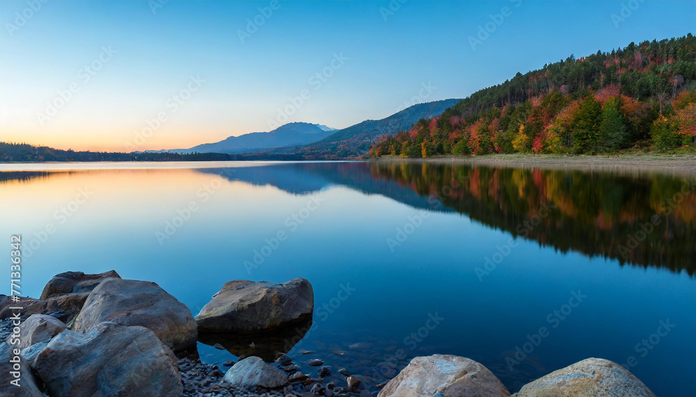 Obraz premium Serene lake, its colors reflecting off the tranquil waters, illuminating the scattered stones