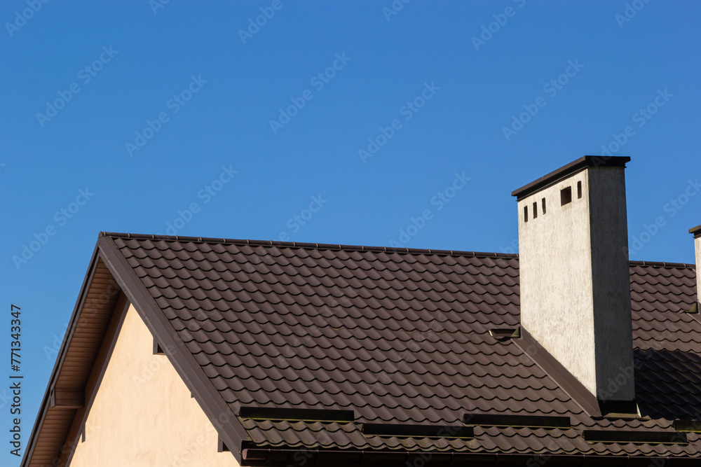 Red house roof with red brick chimney. Ceramic chimney, metal roof tiles, gutters