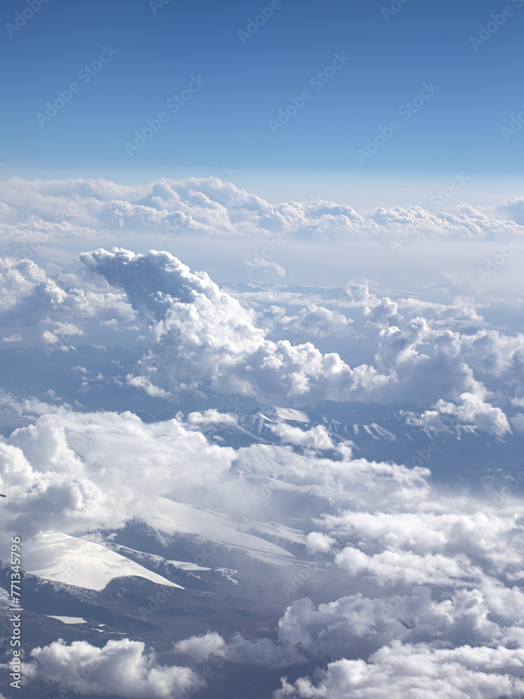 An aerial view of blue sky, white clouds and snow-capped mountains