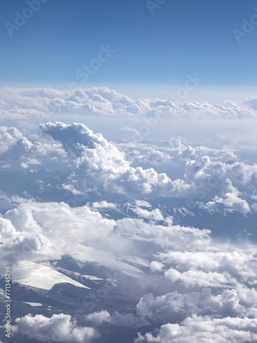 An aerial view of blue sky, white clouds and snow-capped mountains