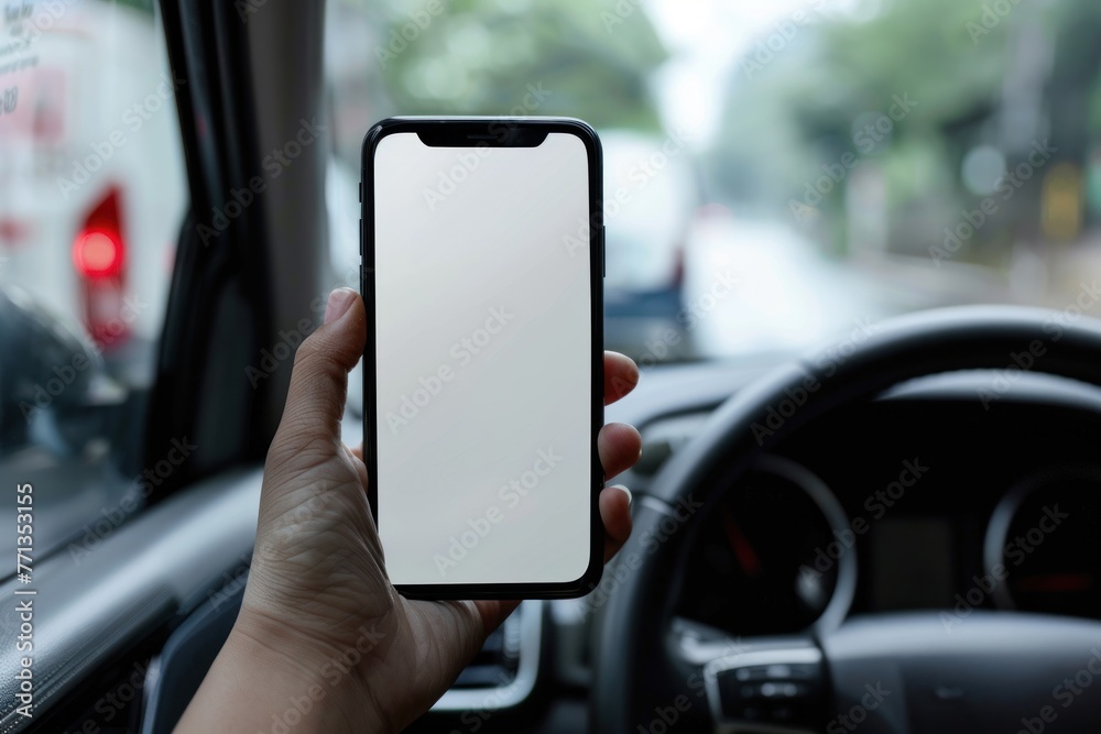 A hand holding a smartphone with a white mockup screen in a car road trip A hand holding a smartphone with a white mockup screen in a car road trip