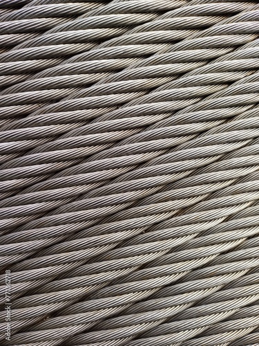 Grey Steelcable, macro shot, vertical, for Background and Industry. Wire rope is composed of two solid, metal wires twisted into a helix that forms a composite rope, in a pattern known as laid rope. photo