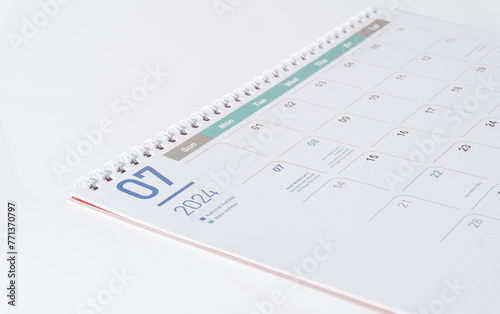 Desk calendar of 2024 laying on white background. July page of 2024 calendar, side view and selective focus shot. 