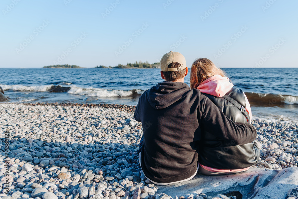 couple sitting on rocky lake coast