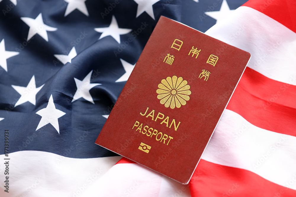 Naklejka premium Japan passport on United States national flag background close up. Tourism and diplomacy concept