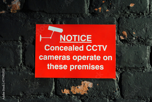 Close Up of Small Red Notice on Old Brick Wall  'Notice Concealed CCTV cameras operate on these premises'  photo