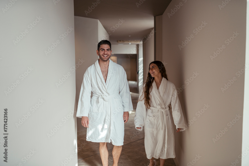 Pareja feliz andando en albornoz por hotel tomando fotos Pareja feliz andando en albornoz por hotel tomando fotos