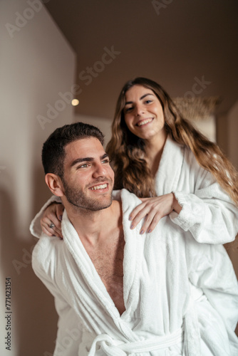 Obraz na płótnie Pareja feliz andando en albornoz por hotel tomando fotos w salonie