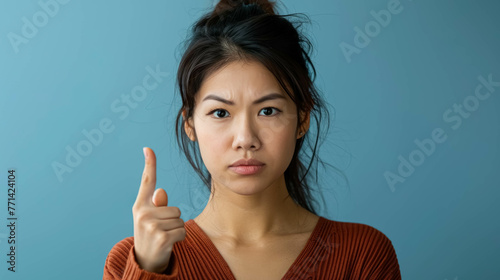 Angry Asian Woman Making A Disapproving Gesture With Her Finger. Conveying a Sense of Disagreement or Refusal photo