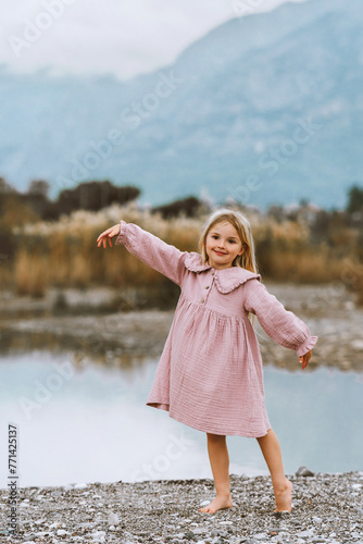 Girl child dancing barefoot on the beach 4 years old kid in muslin dress walking outdoor fashion clothing family lifestyle summer vacations lake and mountains harmony with nature