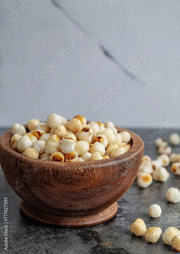 Roasted foxnuts or makhanas served in a wooden bowl on a light gradient grey background photo