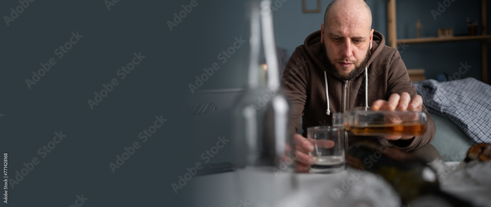 Sad depressed man drinking whisky at home sitting on sofa. Banner.