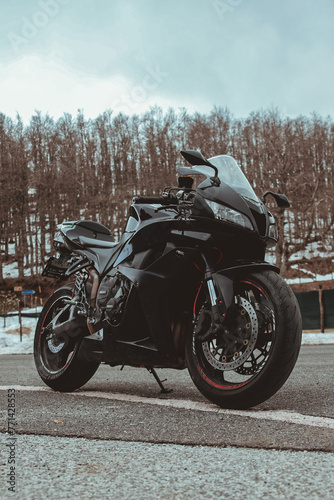 Black colored sports motorcycle parked along a deserted mountain road during a winter day