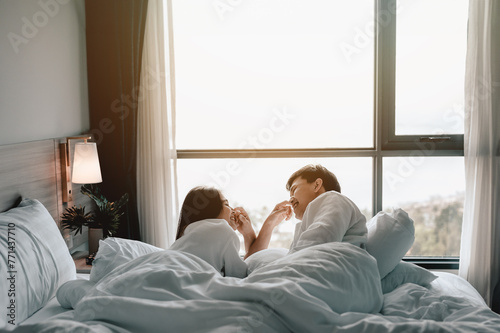 sleeping, romantic, intimacy, comfortable, relaxation, couple, erotic, relationship, bed, intimate. A couple is cuddling on a bed with a view of the ocean. Scene is romantic and peaceful.