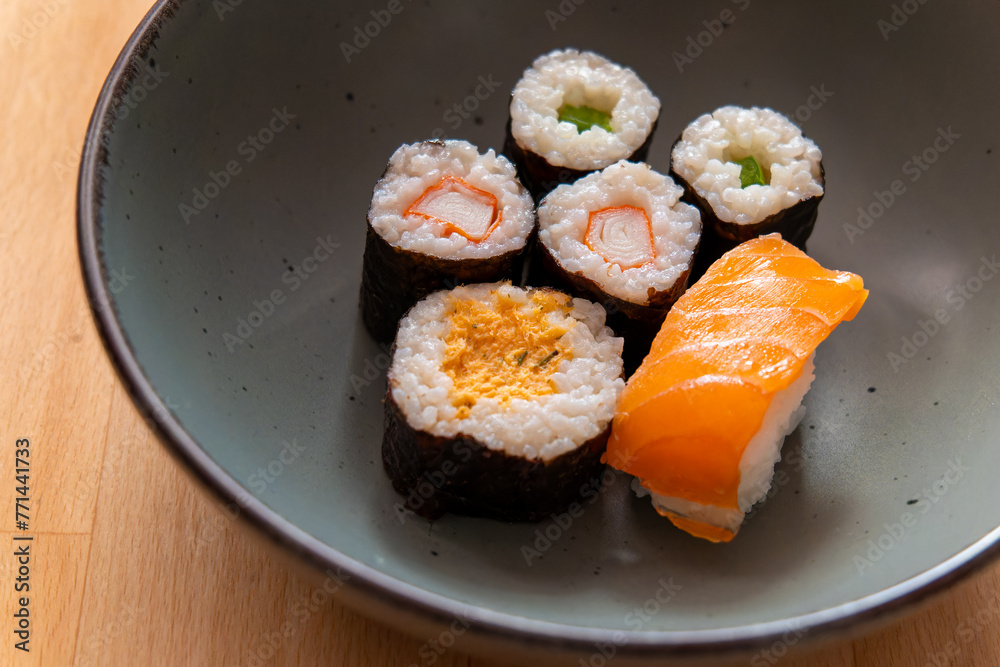 bowl of assorted sushi sits on a wooden table bowl of assorted sushi sits on a wooden table