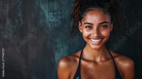 A female fitness model smiling. Dark studio background