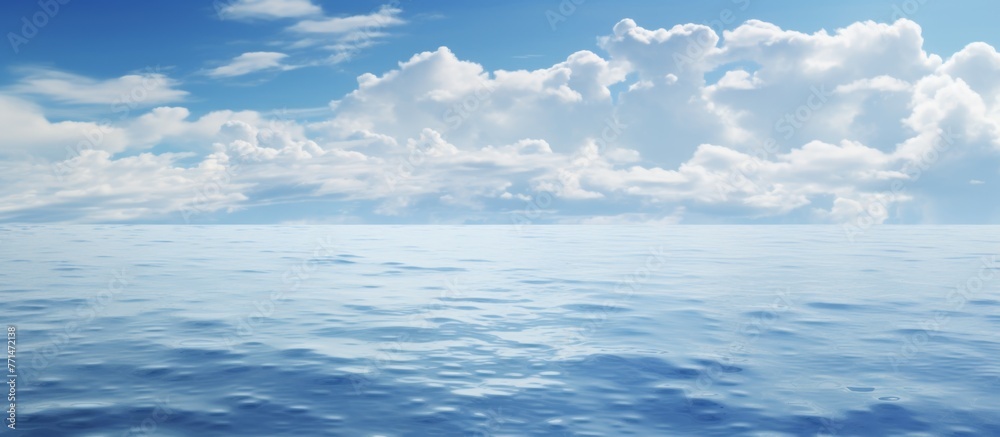 The sun is casting its rays through the cumulus clouds, illuminating the blue ocean water below. A serene natural landscape with wind waves and a distant horizon