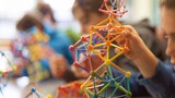 Highlighting hands-on learning in STEM, a detailed macro capture illustrates students engaging with geometric shapes, emphasizing mathematics education.