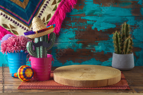 Empty wooden log on  table with cactus decoration over blue wall  background. Mexican party mock up for design and product display